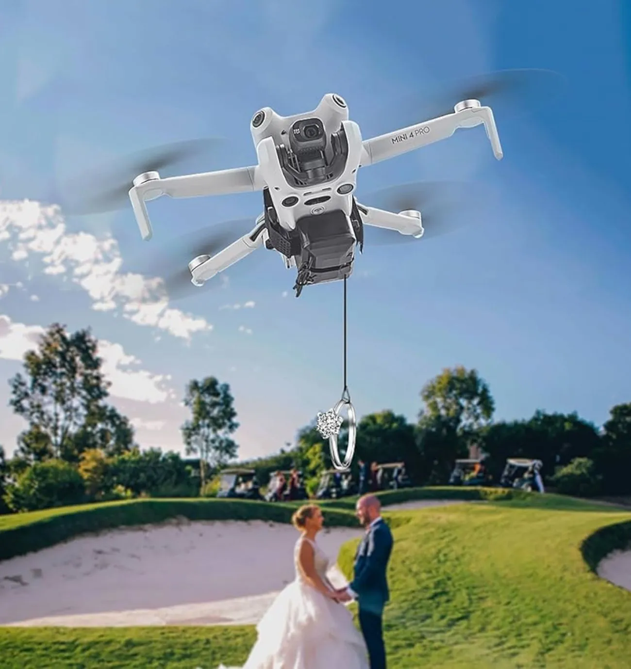 Drone lowering a wedding ring on a line toward a bride and groom on a golf course
