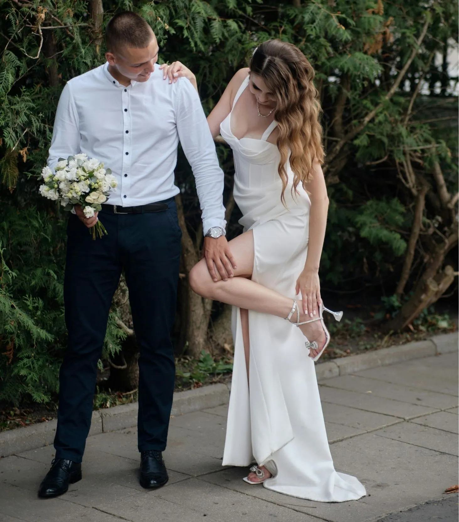 Bride and groom posing together beside a garden path on their wedding day